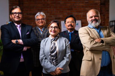 Hintli üst düzey iş adamlarının portresi gülümseyerek alkışlarken, Hintli üst düzey Asyalı yöneticiler modern şirket işyerindeki kameralara bakarak başarıyı alkışlıyor ve kutluyorlar.