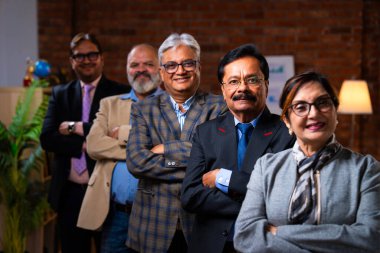 Hintli üst düzey iş adamlarının portresi gülümseyerek alkışlarken, Hintli üst düzey Asyalı yöneticiler modern şirket işyerindeki kameralara bakarak başarıyı alkışlıyor ve kutluyorlar.