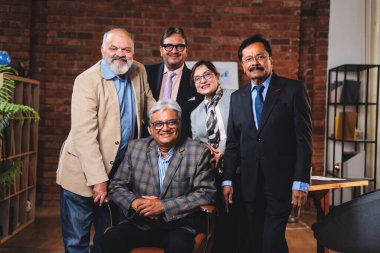 Hintli üst düzey iş adamlarının portresi Hintli üst düzey Asya yöneticileri kılığına girmiş patronun kanat koltuğunda otururken modern şirket ofisinde poz verirken kameraya gülümsüyor.