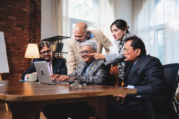 Hintli üst düzey iş adamları, Hindistan 'da üst düzey Asyalı iş adamları olarak birlikte çalışarak, rahat, modern kurumsal işyerlerindeki görevleri incelerken dizüstü bilgisayarları ve masa başındaki kağıtları kullanarak iş birliği yapıyorlar.