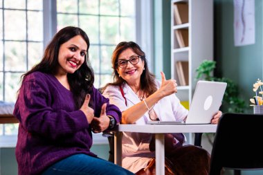 Modern klinikte gülümseyen, kıdemli tıbbi uzmanlık, hasta güveni, pozitif sağlık ilişkisi ve kendine güven gösteren Hintli kadın doktor kameraya bakıyor.