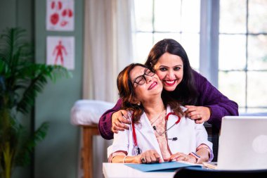 Modern klinikte gülümseyen, kıdemli tıbbi uzmanlık, hasta güveni, pozitif sağlık ilişkisi ve kendine güven gösteren Hintli kadın doktor kameraya bakıyor.