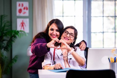 Modern klinikte gülümseyen, kıdemli tıbbi uzmanlık, hasta güveni, pozitif sağlık ilişkisi ve kendine güven gösteren Hintli kadın doktor kameraya bakıyor.