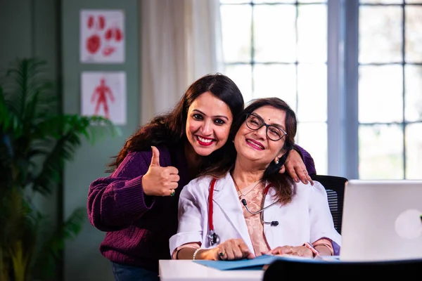 Modern klinikte gülümseyen, kıdemli tıbbi uzmanlık, hasta güveni, pozitif sağlık ilişkisi ve kendine güven gösteren Hintli kadın doktor kameraya bakıyor.