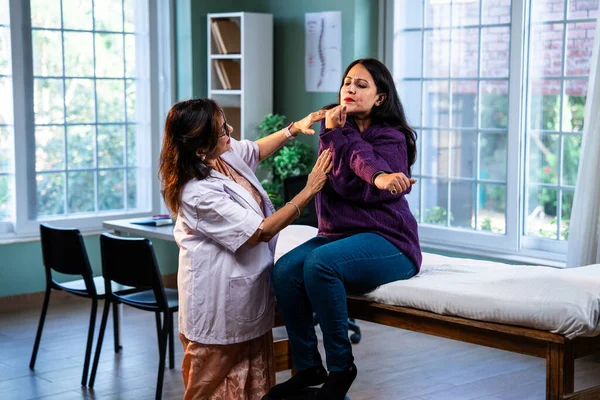 Hintli bayan fizyoterapist, modern klinikte rehberli egzersiz sırasında genç bayan hastalara omuz güçlendirmeyi öğreterek, ağrı kesici ve rehabilitasyon terapisinde uzman olduğunu gösteriyor.