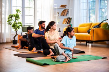 Hint ailesi evde yog asana yapıyor. Matsyendrasana, sakin bir sabah saatinde evde birlikte omurga bükme yogası yapıyor. Modern, savurgan bir yaşam alanında, sağlığını destekliyor.