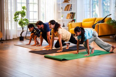 Hintli aile evde Suryanamaskara yapıyor. Sağlıklı vücut için evde güneş selamı yogası yapıyorlar. Ve sabahları modern, savurgan bir yaşam alanında sakin bir zihin.