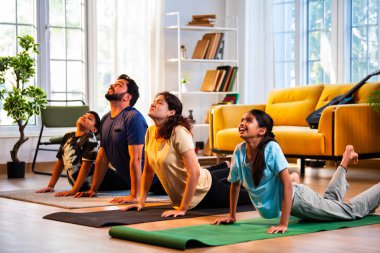 Hintli aile evde Suryanamaskara yapıyor. Sağlıklı vücut için evde güneş selamı yogası yapıyorlar. Ve sabahları modern, savurgan bir yaşam alanında sakin bir zihin.