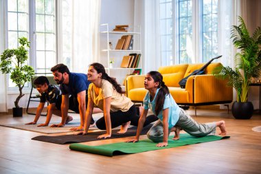 Hintli aile evde Suryanamaskara yapıyor. Sağlıklı vücut için evde güneş selamı yogası yapıyorlar. Ve sabahları modern, savurgan bir yaşam alanında sakin bir zihin.