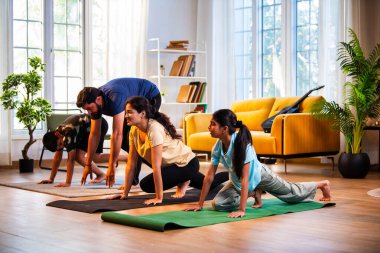 Hintli aile evde Suryanamaskara yapıyor. Sağlıklı vücut için evde güneş selamı yogası yapıyorlar. Ve sabahları modern, savurgan bir yaşam alanında sakin bir zihin.