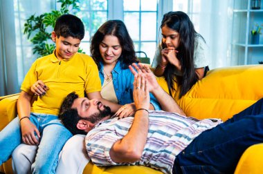 Hintli genç baba evdeki aileye bir hikaye anlatıyor. Oğul ve kız olarak karın kucağında dinlenirken. Kapalı koltukta mutlu bir şekilde dinle.