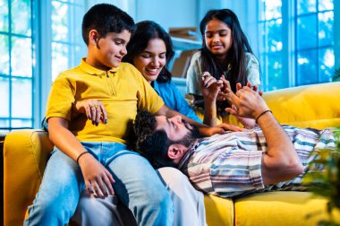 Hintli genç baba evdeki aileye bir hikaye anlatıyor. Oğul ve kız olarak karın kucağında dinlenirken. Kapalı koltukta mutlu bir şekilde dinle.