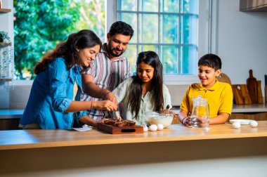 Hint ailesi, modern mutfakta kek hamuru yaparken genç ebeveynler, hamuru karıştırırken kaliteli zaman geçirmenin, bağ kurmanın ve neşeli ev yemeği pişirmenin keyfini çıkarıyorlar.
