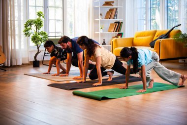 Hintli aile evde Suryanamaskara yapıyor. Sağlıklı vücut için evde güneş selamı yogası yapıyorlar. Ve sabahları modern, savurgan bir yaşam alanında sakin bir zihin.