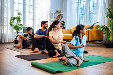 Hint ailesi evde yog asana yapıyor. Matsyendrasana, sakin bir sabah saatinde evde birlikte omurga bükme yogası yapıyor. Modern, savurgan bir yaşam alanında, sağlığını destekliyor.