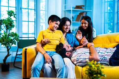 Hintli genç baba evdeki aileye bir hikaye anlatıyor. Oğul ve kız olarak karın kucağında dinlenirken. Kapalı koltukta mutlu bir şekilde dinle.