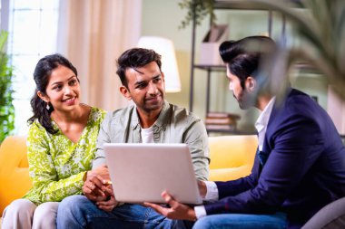 Hintli çift yatırım toplantısı sırasında temsilciyle tartışıyor. İş adamlarıyla mali belgeleri ve dosyaları gözden geçiriyorlar. Bu sırada rahat, modern oturma odasındaki koltukta oturuyorlar.