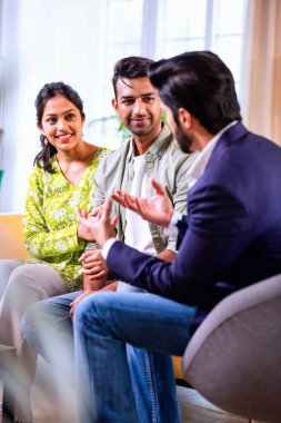 Hintli çift yatırım toplantısı sırasında temsilciyle tartışıyor. İş adamlarıyla mali belgeleri ve dosyaları gözden geçiriyorlar. Bu sırada rahat, modern oturma odasındaki koltukta oturuyorlar.