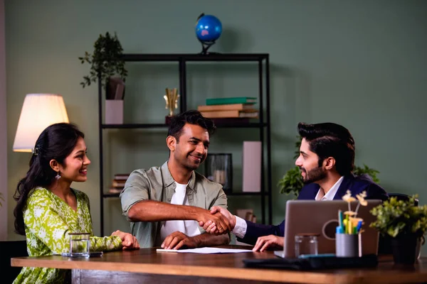 Hintli çift belgeleri imzalarken, detaylı yatırım tartışması sırasında ofisinde finans planlamacısıyla tokalaşırken, samimi şirket içi ortamında masada otururken,