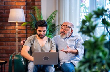 Hintli genç oğul ve kıdemli baba, modern evdeki kanepede oturup çevrimiçi işleri, iş ve mali konuları tartışırken, nesillerdir kapalı alanlarda kaynaşıyorlar.