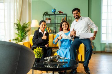 Hintli genç mutlu çift, gelecekteki planları için mali ya da yasal konuları tartıştıktan sonra ev toplantısı sırasında onaylayan kadın şirket danışmanından belge alıyor.