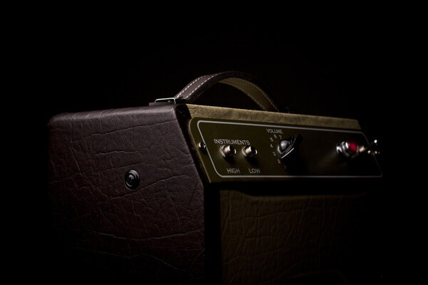 Horizotal picture of a leather finished guitar amplifier on black background viewed from the side