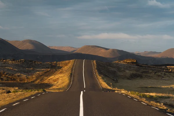 Straight and empty asphalt road going over the hills — Stock Photo, Image