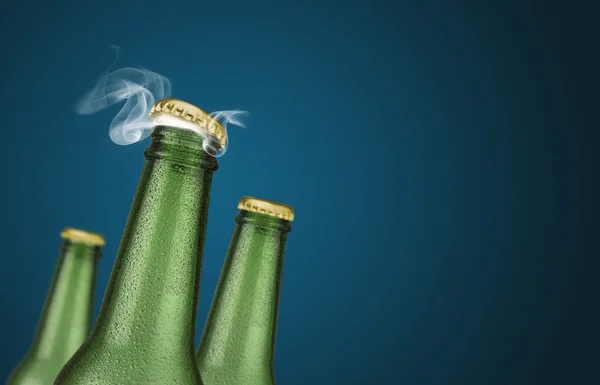 Tres botellas de cerveza verde sobre fondo azul — Foto de Stock