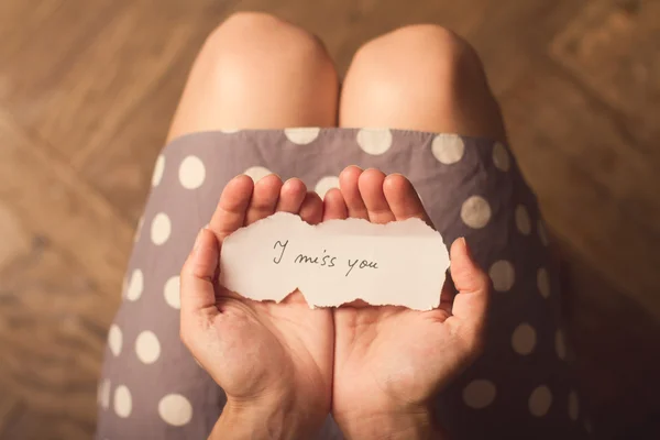 Mujer sosteniendo una nota de papel con el texto Te extraño — Foto de Stock