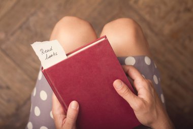 Kırmızı bir kitap ile bir kağıt bitti iletisi tutan kadın