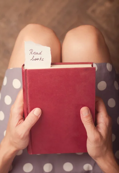 Kırmızı bir kitap ile bir kağıt bitti iletisi tutan kadın