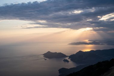 Türkiye 'de yaz mevsiminde Oludeniz Mavi Göl kıyısında gün batımında Akdeniz üzerinde yükselen Babadag yüksek dağlarının zirvesinden güzel hava manzarası
