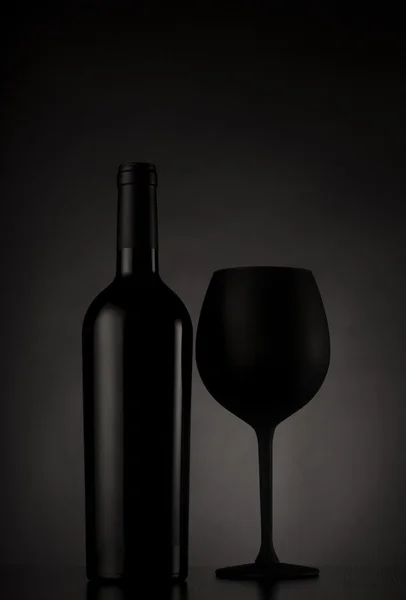 Garrafa de vinho preto e copo de vinho preto — Fotografia de Stock