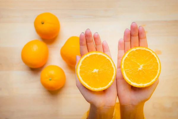 Close Up hand holding half orange fruit on the table wooden. Orange fruit raw material for make juice.