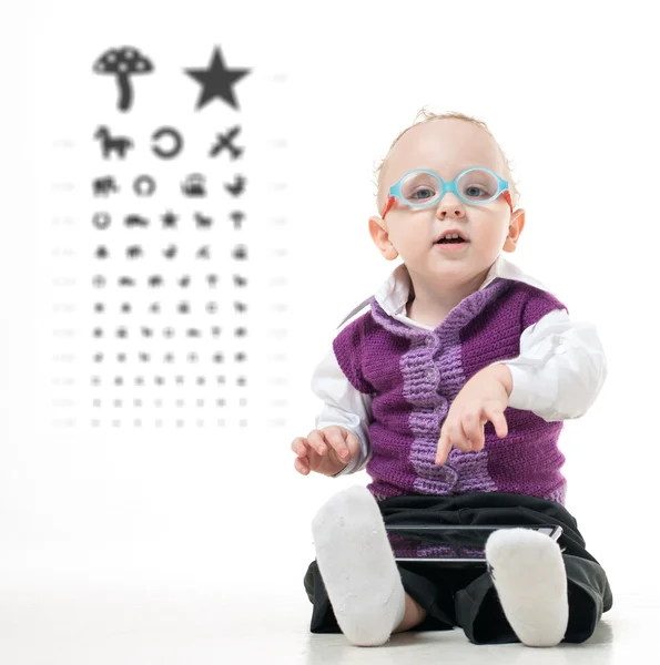 Bir göz muayenesi için tablonun arka planda gözlüklü çocuk yere oturur
