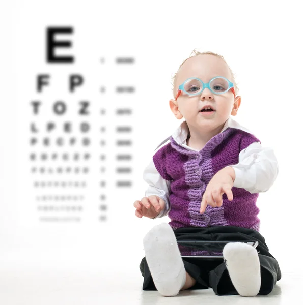 Bir göz muayenesi için tablonun arka planda gözlüklü çocuk yere oturur