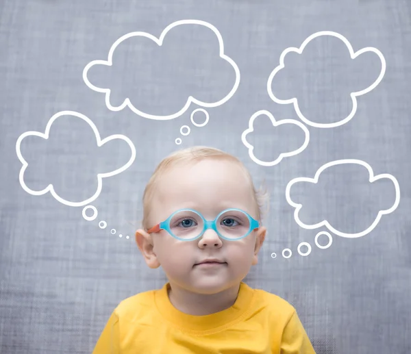 Menino muito inteligente com óculos em um fundo cinza com nuvens — Fotografia de Stock