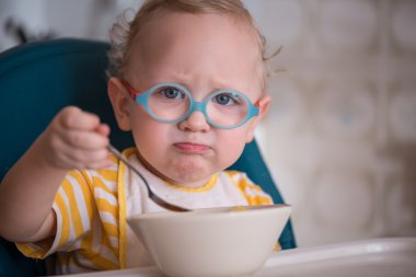 Little boy with glasses naughty and does not want to eat porridge clipart