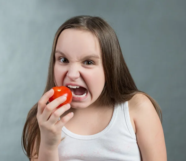 Девочка гневно грызет помидоры — стоковое фото