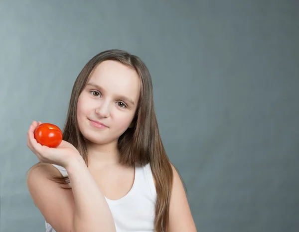 Красивая маленькая девочка с помидором в руке — стоковое фото