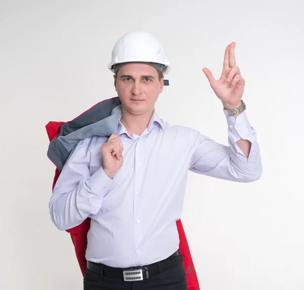 Mężczyzna w czerwonej kurtce, trzymając rękę kask biały budowlanych — Zdjęcie stockowe