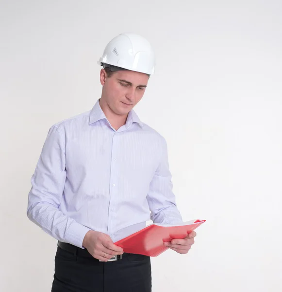 Człowiek w kasku biały budowlanych czerwony folder w ręce trzyma — Zdjęcie stockowe