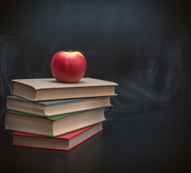 Kitaplar ve arka plan siyah okul yönetimi üzerinde sulu elma yığını