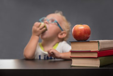 Neşeli bebek ile bir elma yemek beyaz bir gömlek gri bir arka plan üzerinde