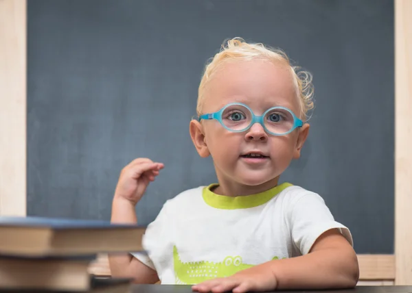 Ребенок в очках сидит за столом с книгами — стоковое фото