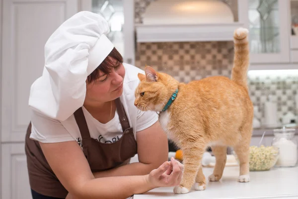 Девушка в кухонном фартуке и в шапке шеф-повара, готовящая пироги — стоковое фото