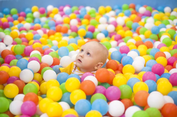 En liten pojke i en torr bassäng med färgade bollar — Stockfoto