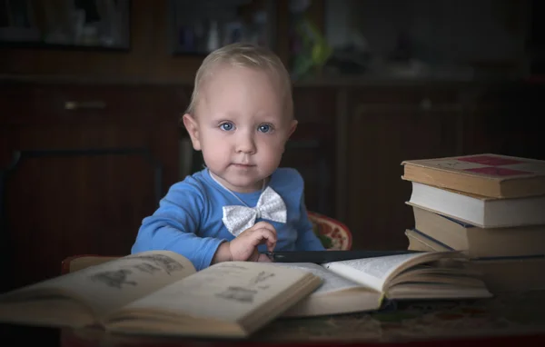 Умный маленький мальчик сидит за столом с книгами — стоковое фото