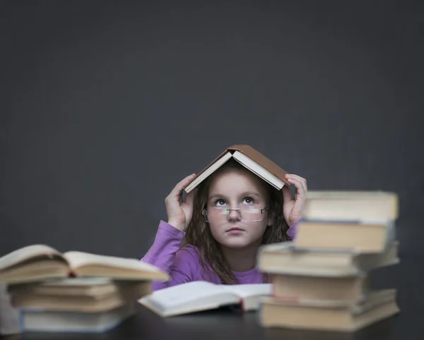 The girl in glasses hidden under a book — Stock Photo, Image