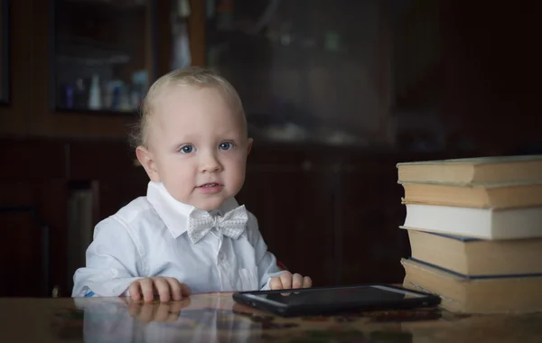 Умный маленький мальчик сидит за столом с книгами — стоковое фото